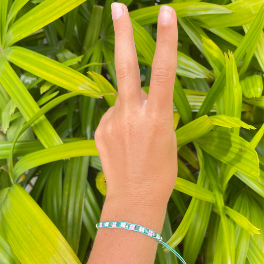 tween girl peace sign with hand wearing the rice bead mermaid bracelet